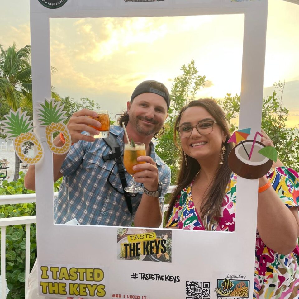 Couple raising drinks inside a Taste the Keys photo frame