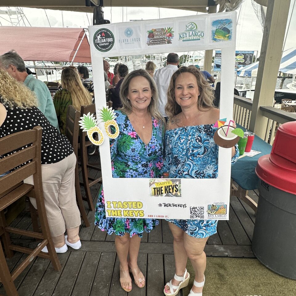 Two women in tropical print dresses posing in a photo frame