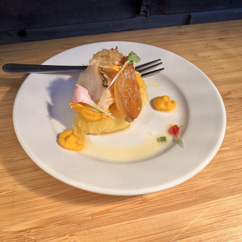 Plated dessert with mango sauce and edible flowers