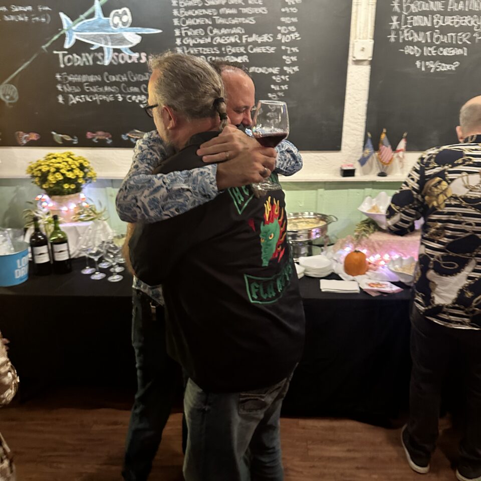 Two guests hugging near a chalkboard menu