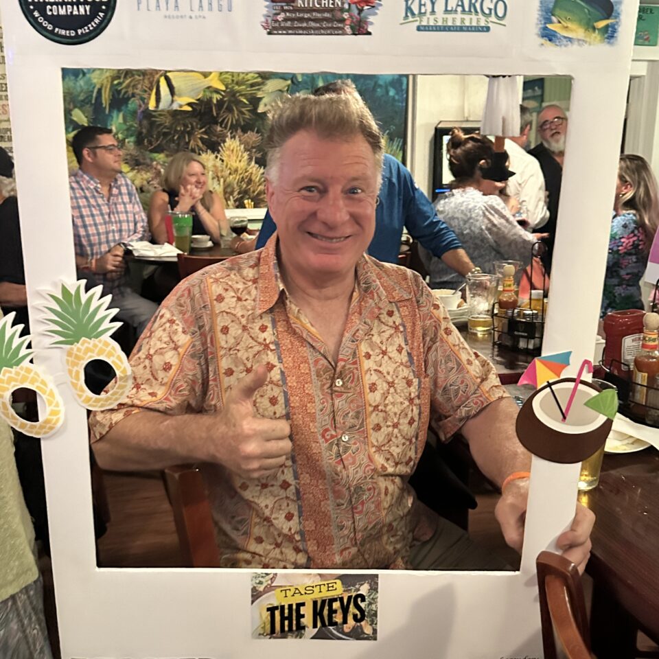 Smiling man giving a thumbs-up inside a Taste the Keys photo frame