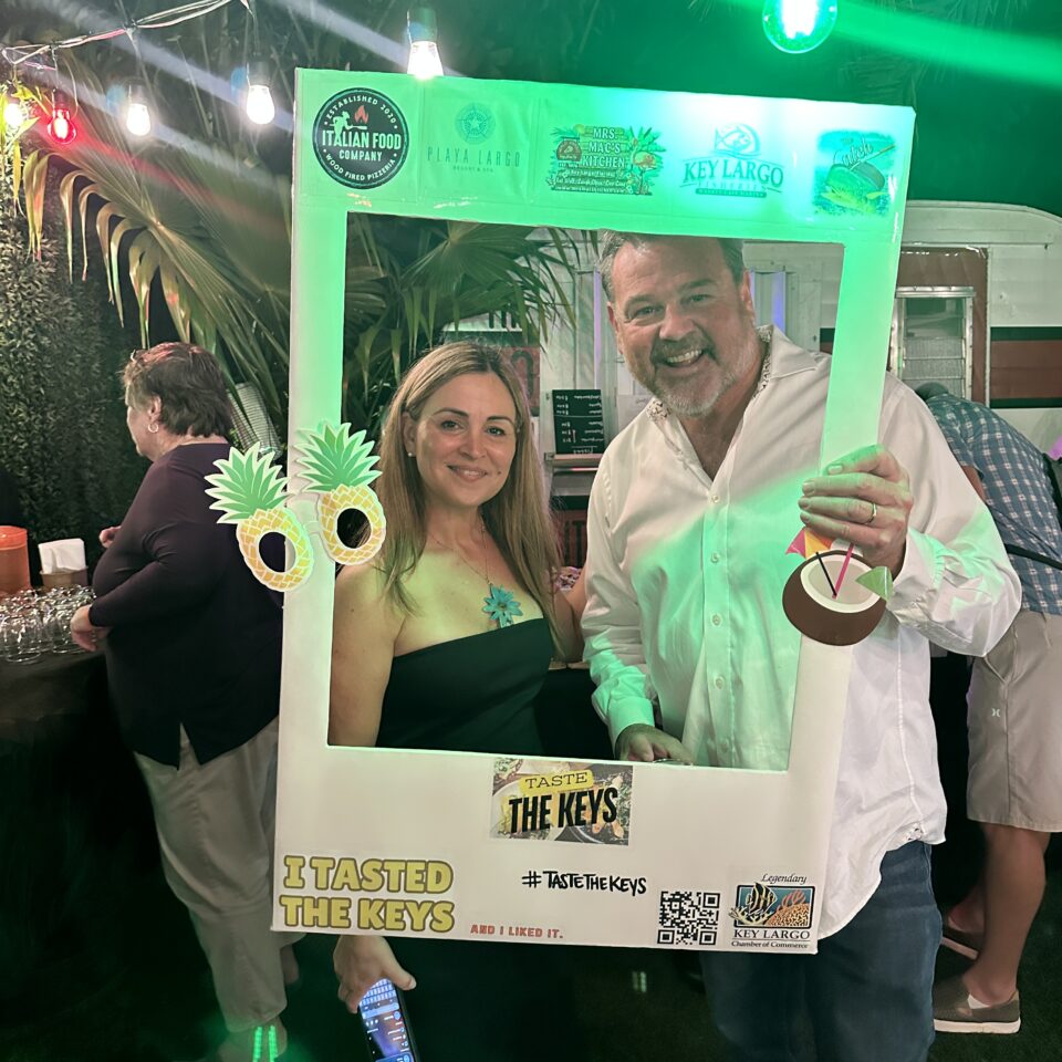 Two guests posing with a Taste the Keys photo frame