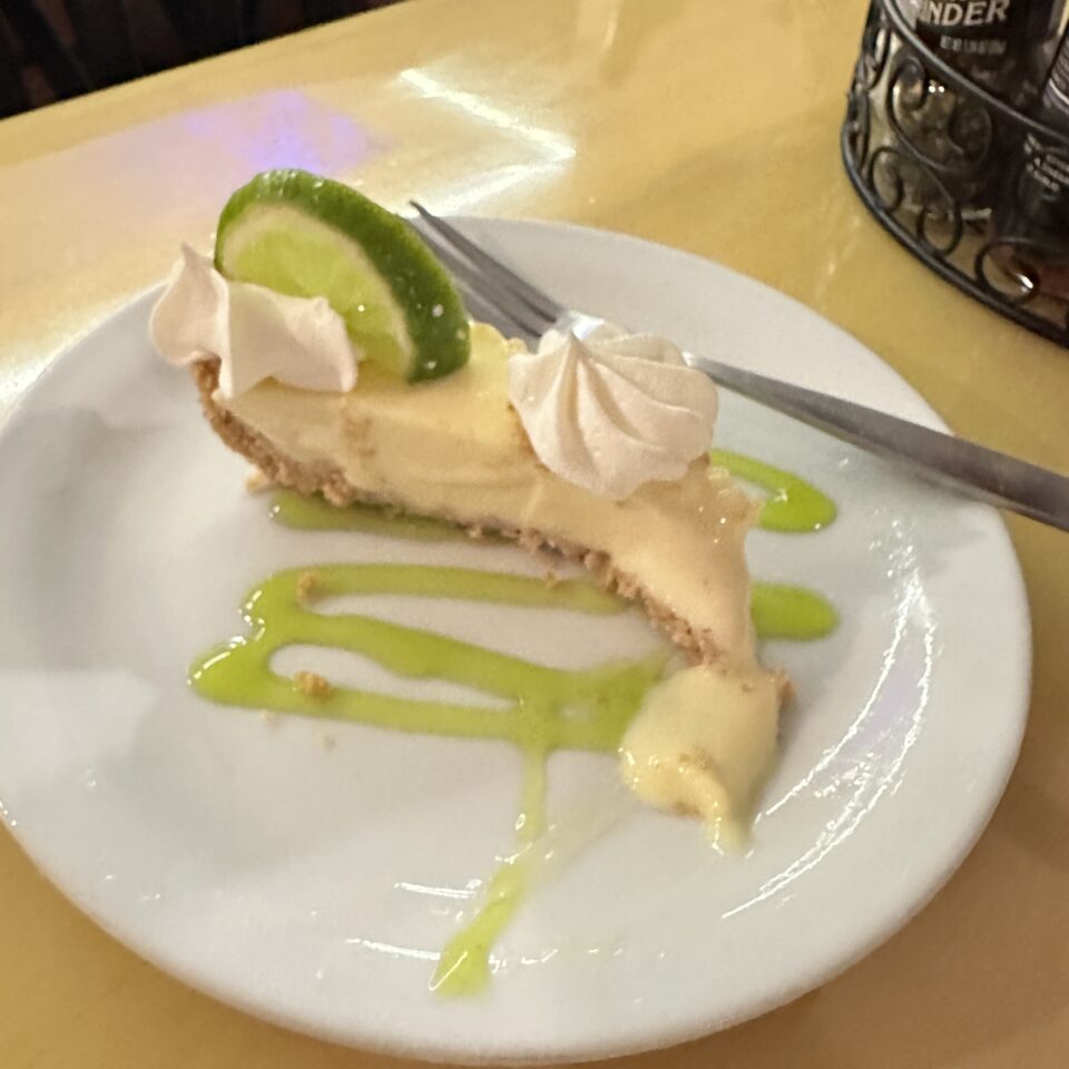 Slice of key lime pie with a lime wheel and whipped cream