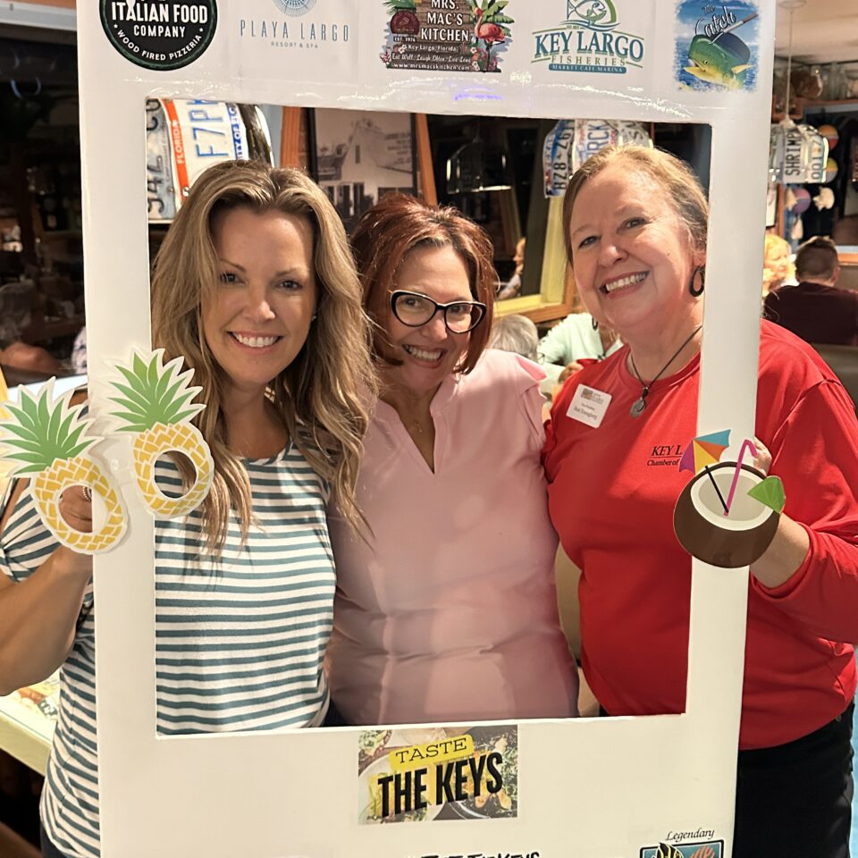 Three women posing inside a Taste the Keys photo frame