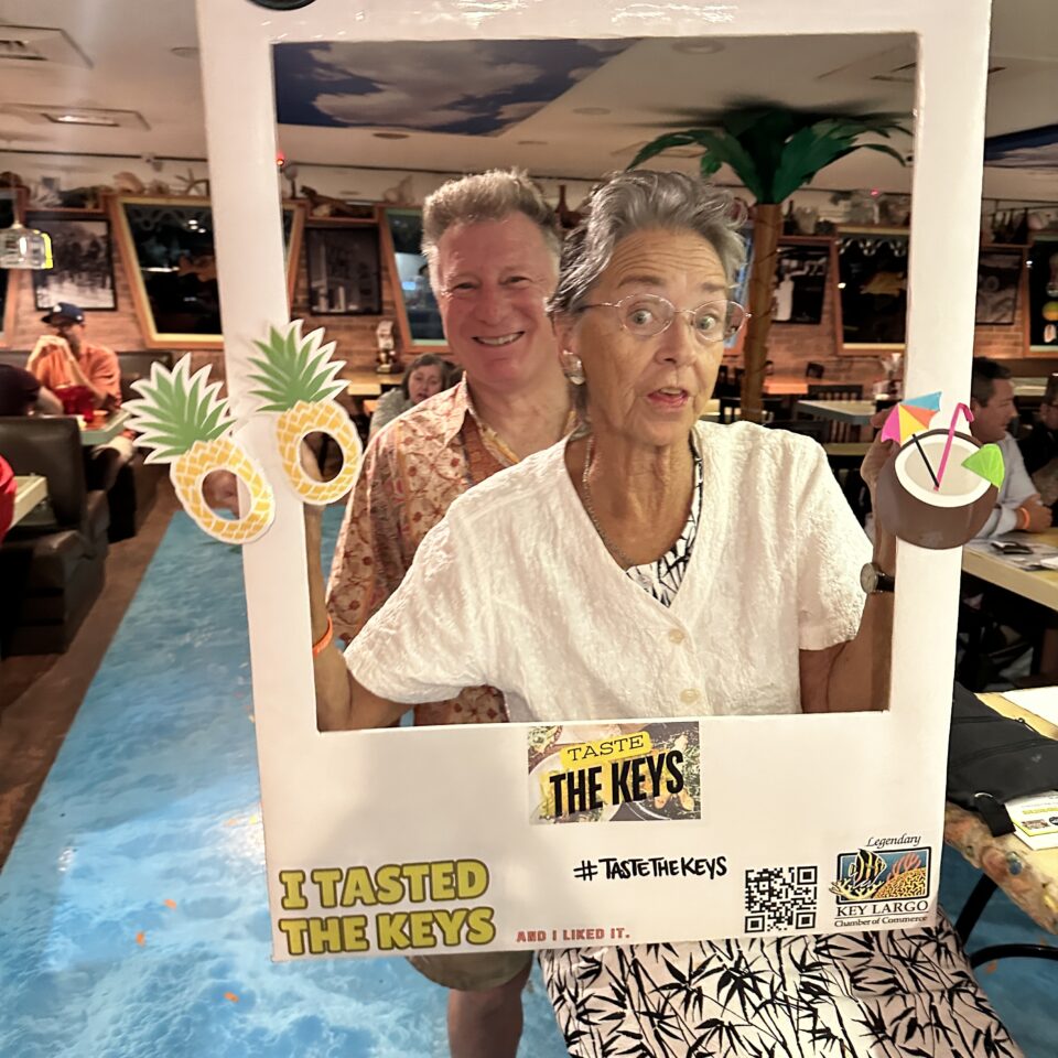 Guests posing in a Taste the Keys photo frame inside a restaurant