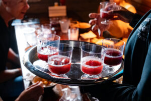 Server holding a tray of red sangria tasting cups