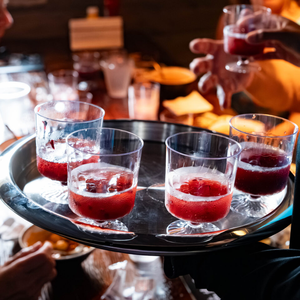 Server holding a tray of red sangria tasting cups