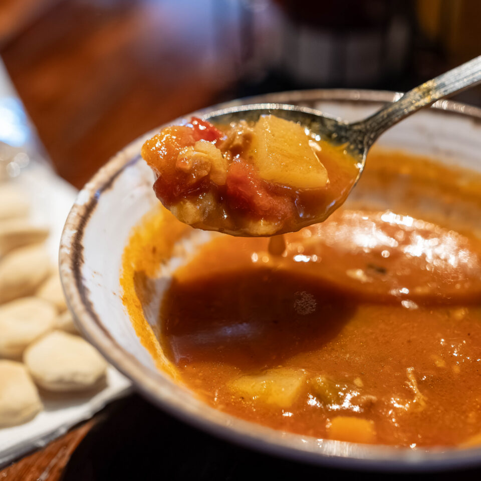 Spoonful of seafood stew lifted from a bowl