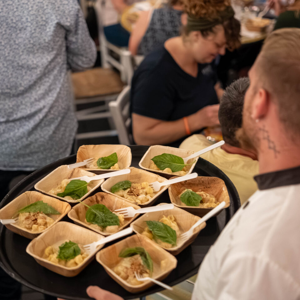 Chef holding a tray of small tasting boats garnished with herbs