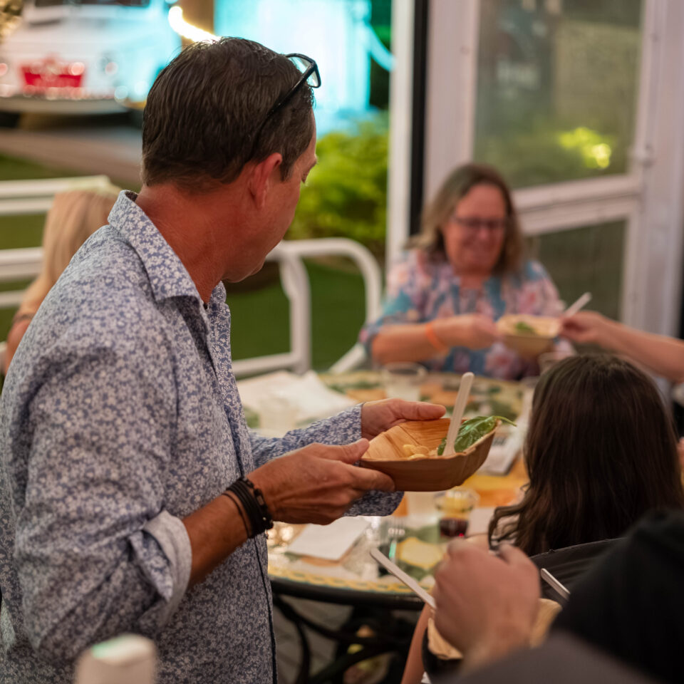 Guest passing a small plate across a crowded table