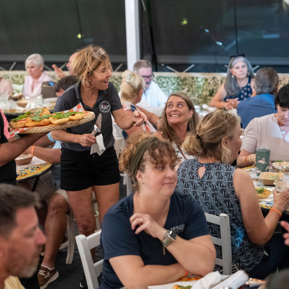 Server carrying a tray of bites through a busy outdoor dining room