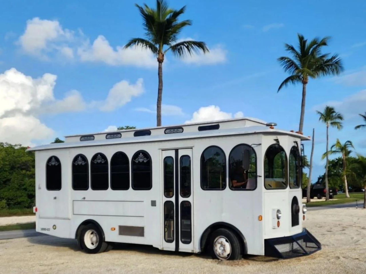 The white Taste the Keys trolley parked under palm trees
